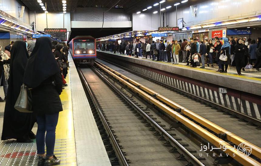 ایستگاه مترو تهران در زیرزمین، قطار درحال ورود به سکو و جمعیت مسافران منتظر ایستاده در ایستگاه